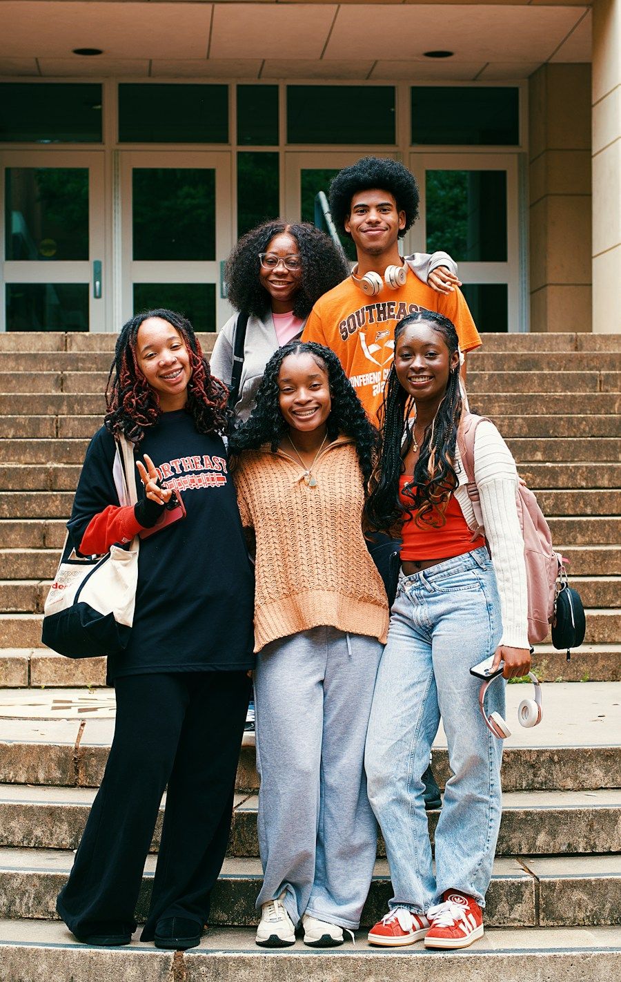 Groupe d'amis étudiants souriant sur des marches